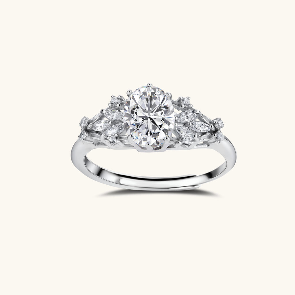 Sterling silver ring with oval moissanite center stone surrounded by smaller accent stones in ornate setting
